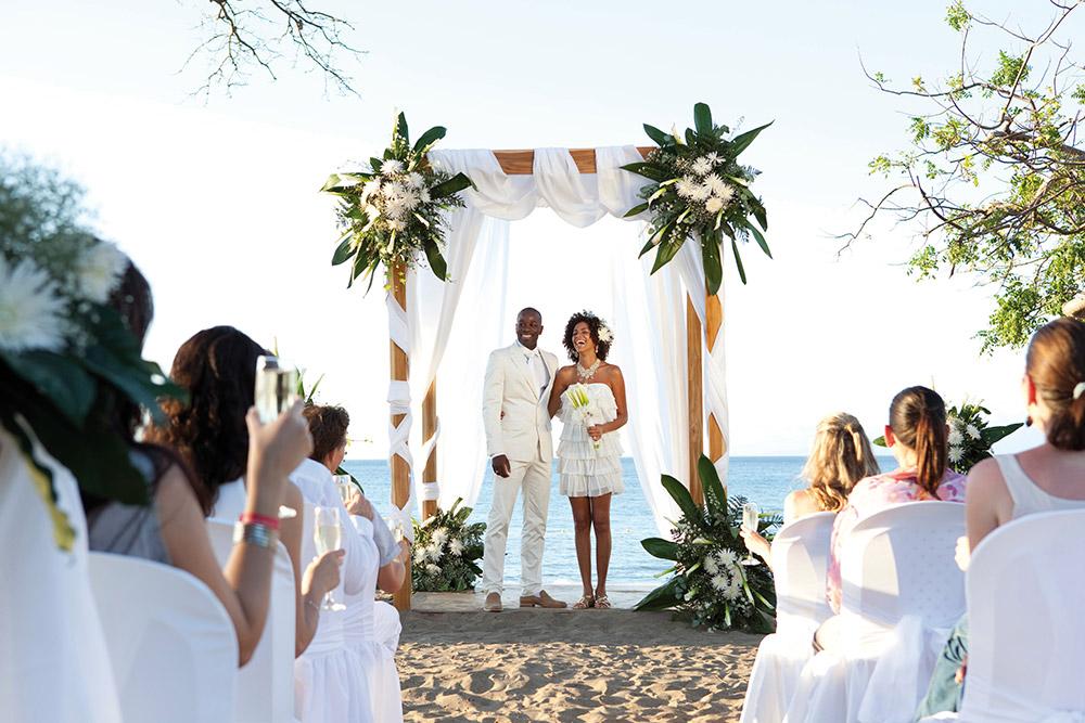 Couple facing wedding guests during wedding ceremony on the beach at Hotel Riu Guanacaste.