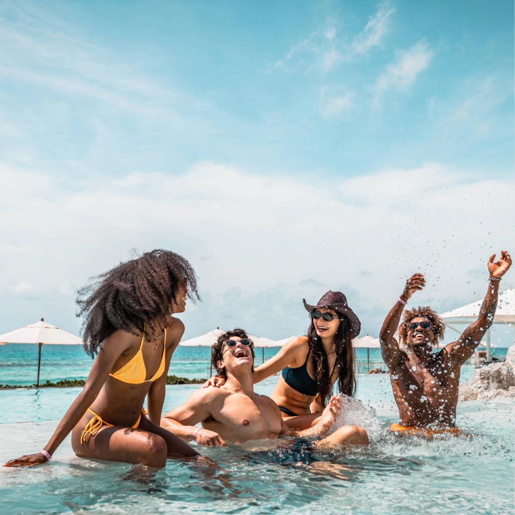 Friends enjoying a beachfront pool at an all-inclusive AIC Hotel Group resort