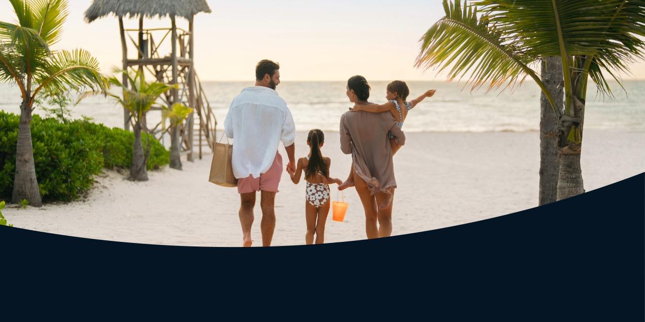 Family with two children walking along sandy beach toward the ocean