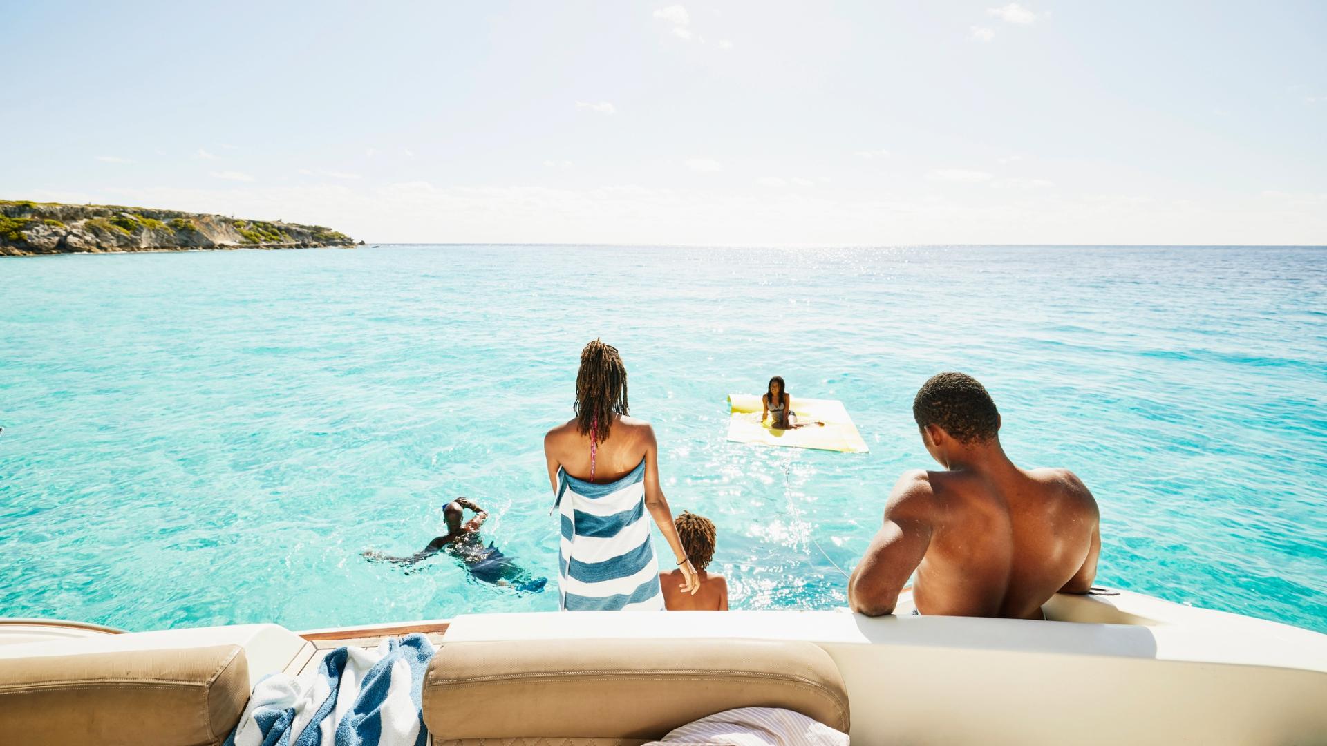 Family on a boat relaxing and swimming together in turquoise ocean water