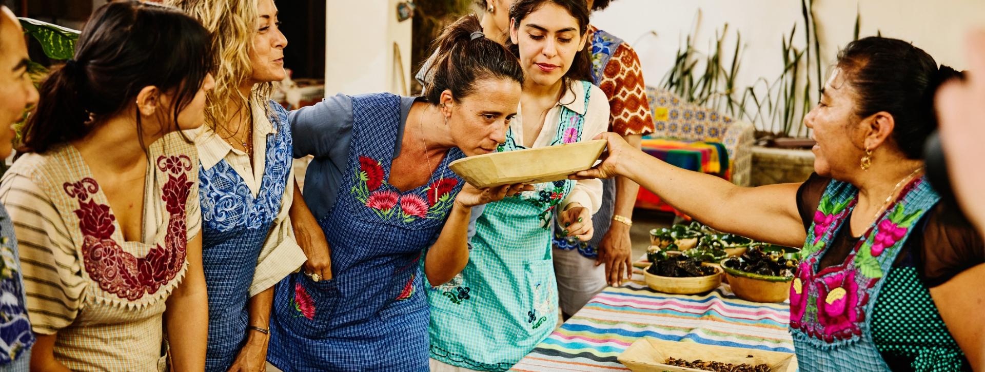 Group of women in aprons smelling ingredients during a cooking class