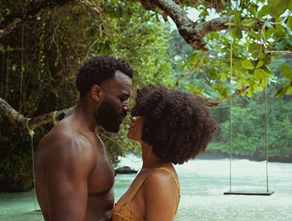 Young couple romantically canoodling in tropical setting 