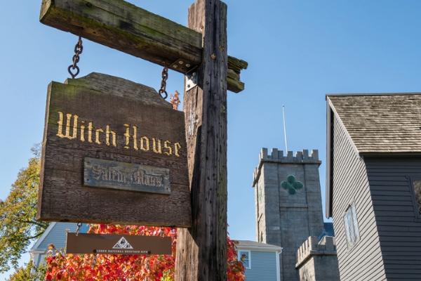Wooden Witch House sign in front of historic buildings in Salem, Massachusetts.