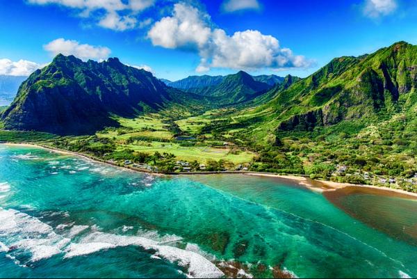 Aerial view of turquoise ocean meeting lush green mountains along the coast