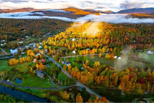 Aerial view of Vermont town surrounded by colorful fall foliage and mountains