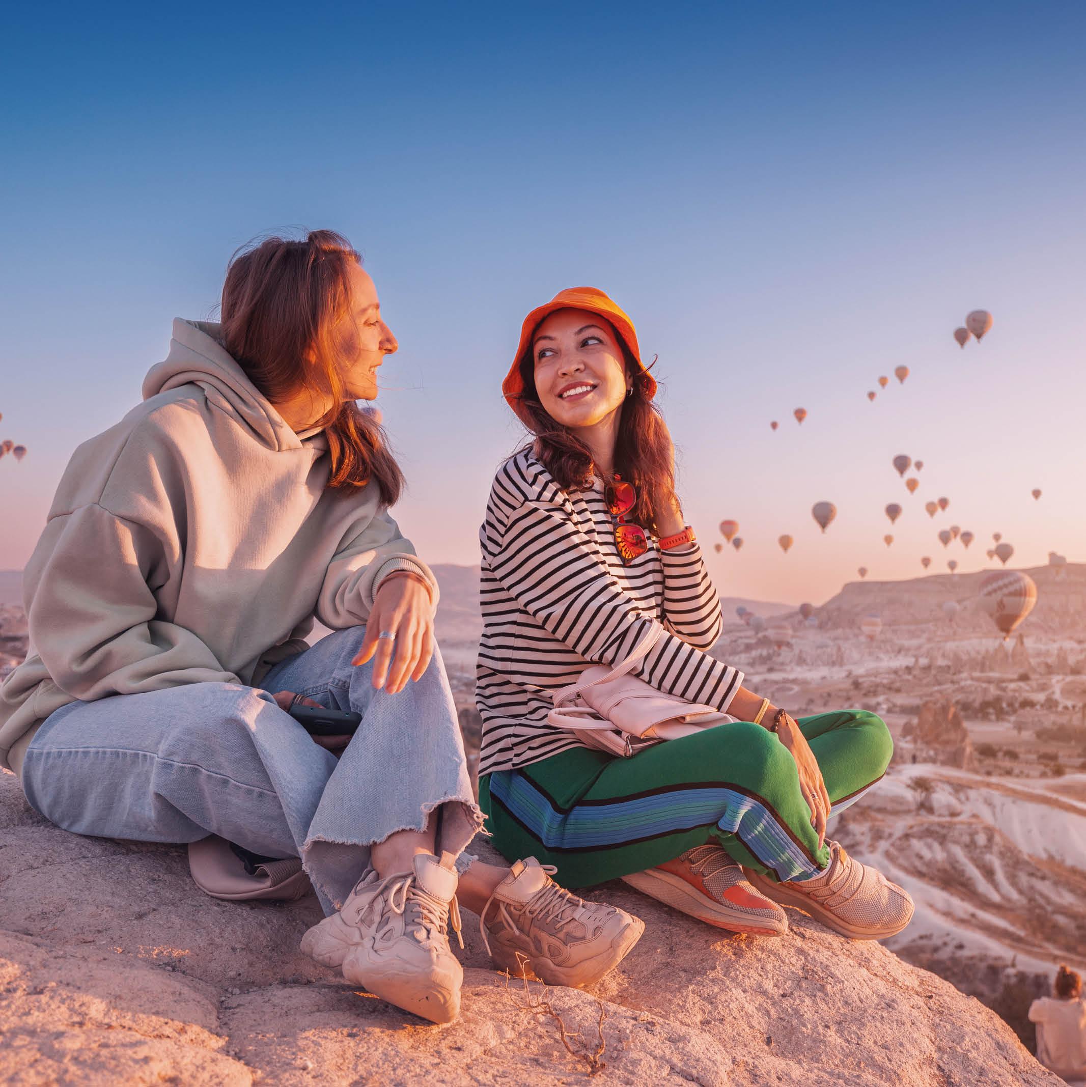 Two female travelers with hot air balloons behind them
