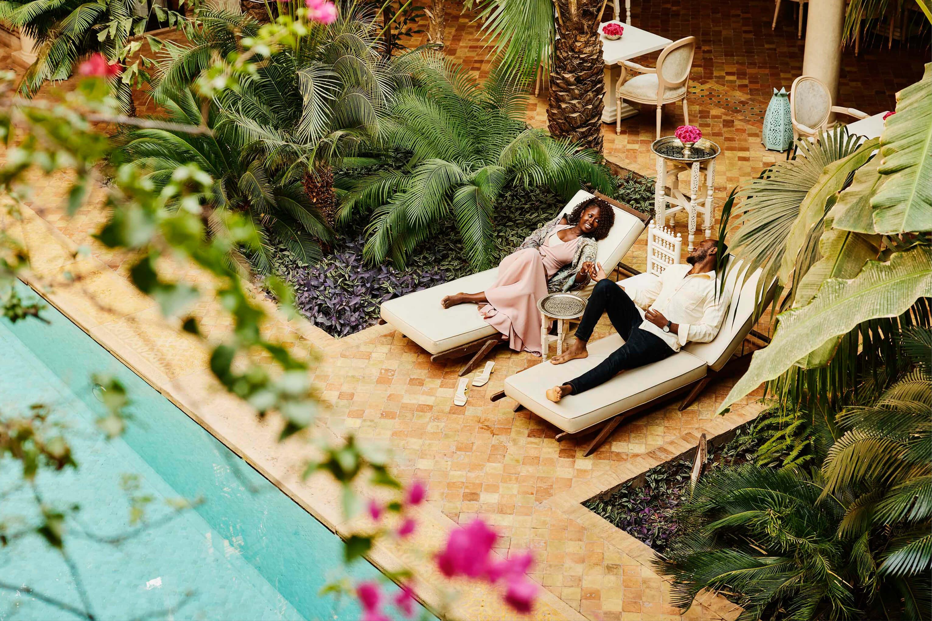 A couple relaxes on lounge chairs beside a sparkling pool, enjoying a sunny day together at an adults only resort