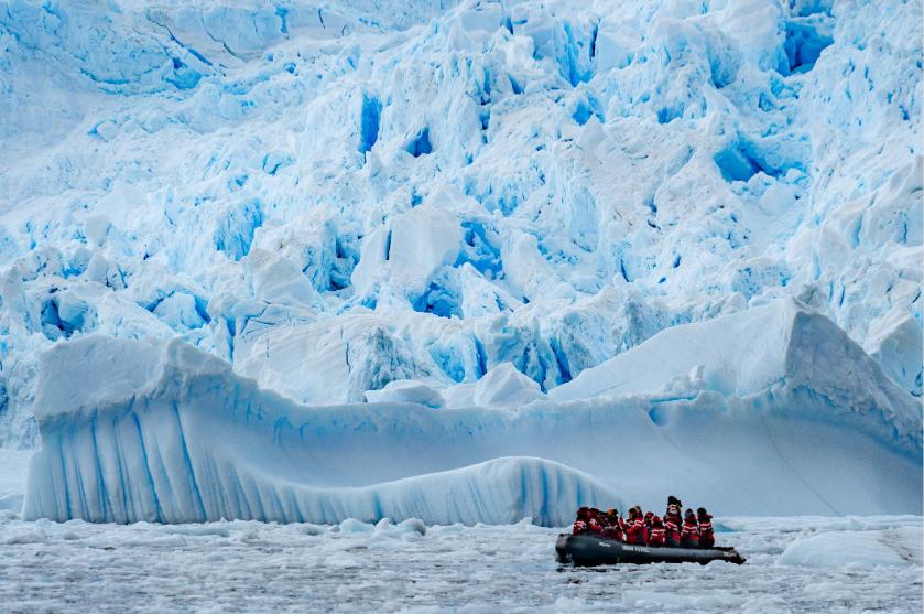 Travelers on a small-ship expedition cruise explore a towering glacier in Antarctica.