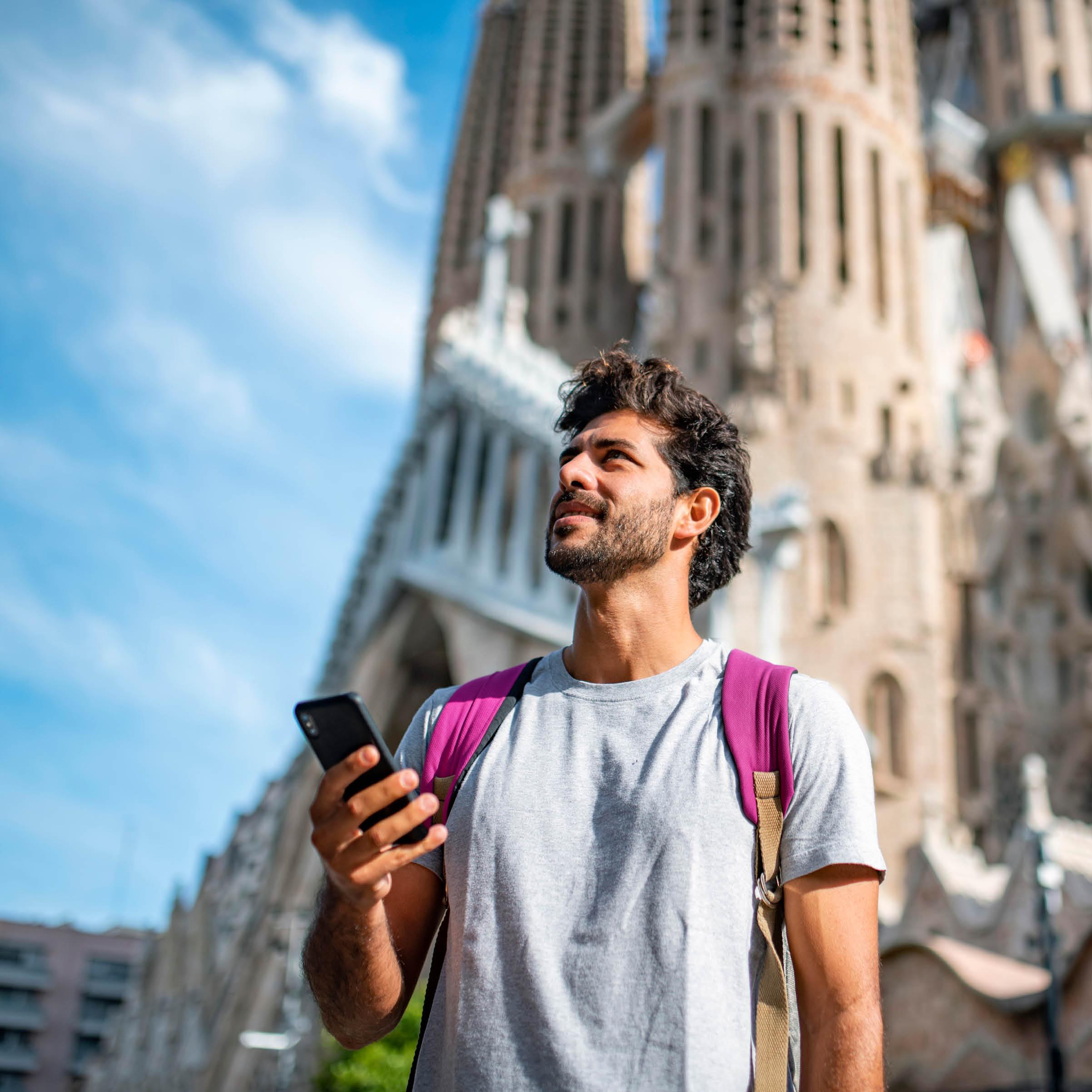 A man holding his mobile phone with a gothic structure in the background