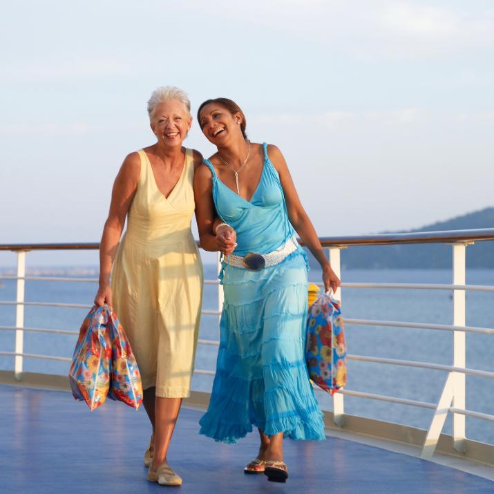 Two travelers laughing together while enjoying a sunny day on a cruise ship.