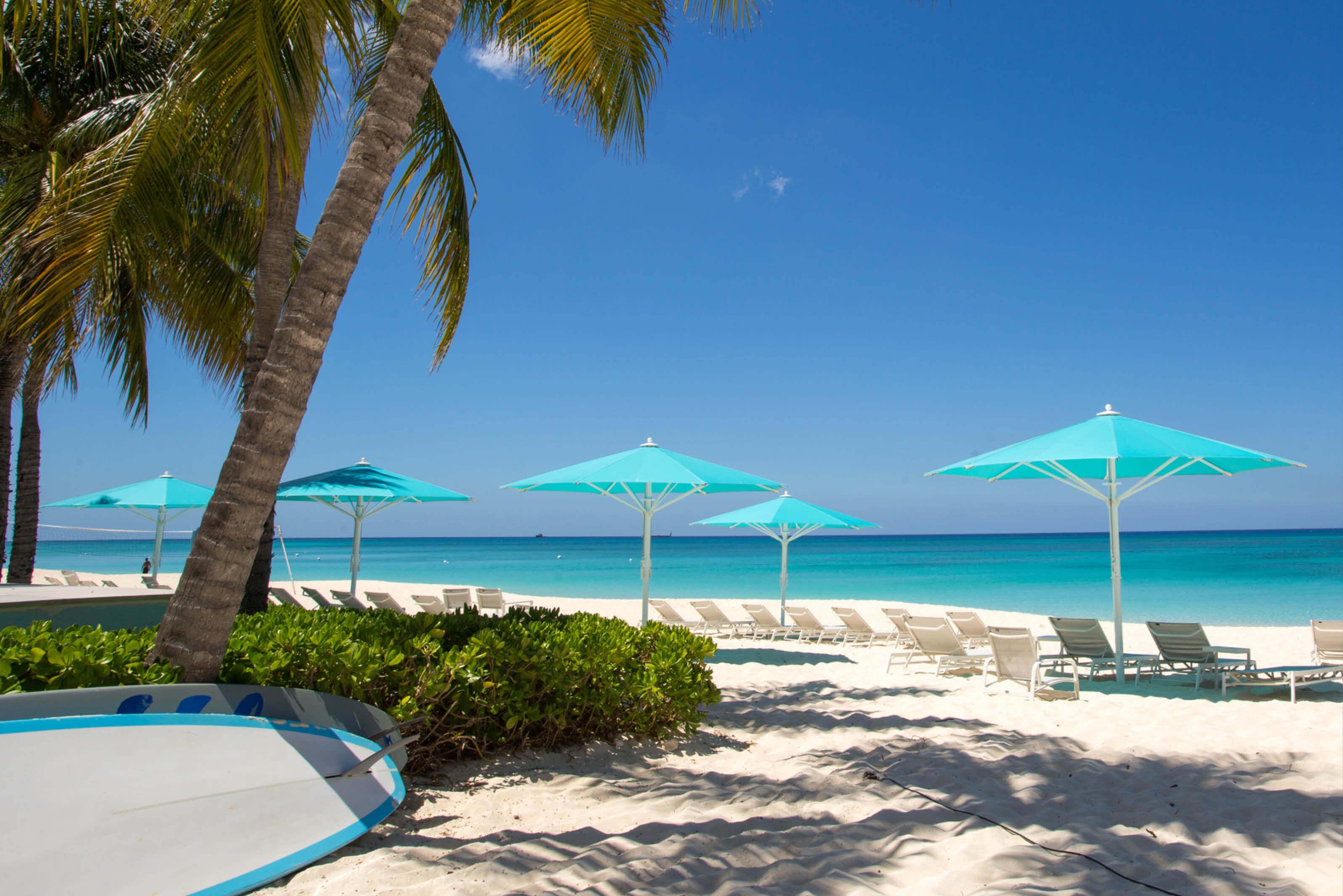A serene beachfront with turquoise umbrellas on Seven Mile Beach in the Cayman Islands