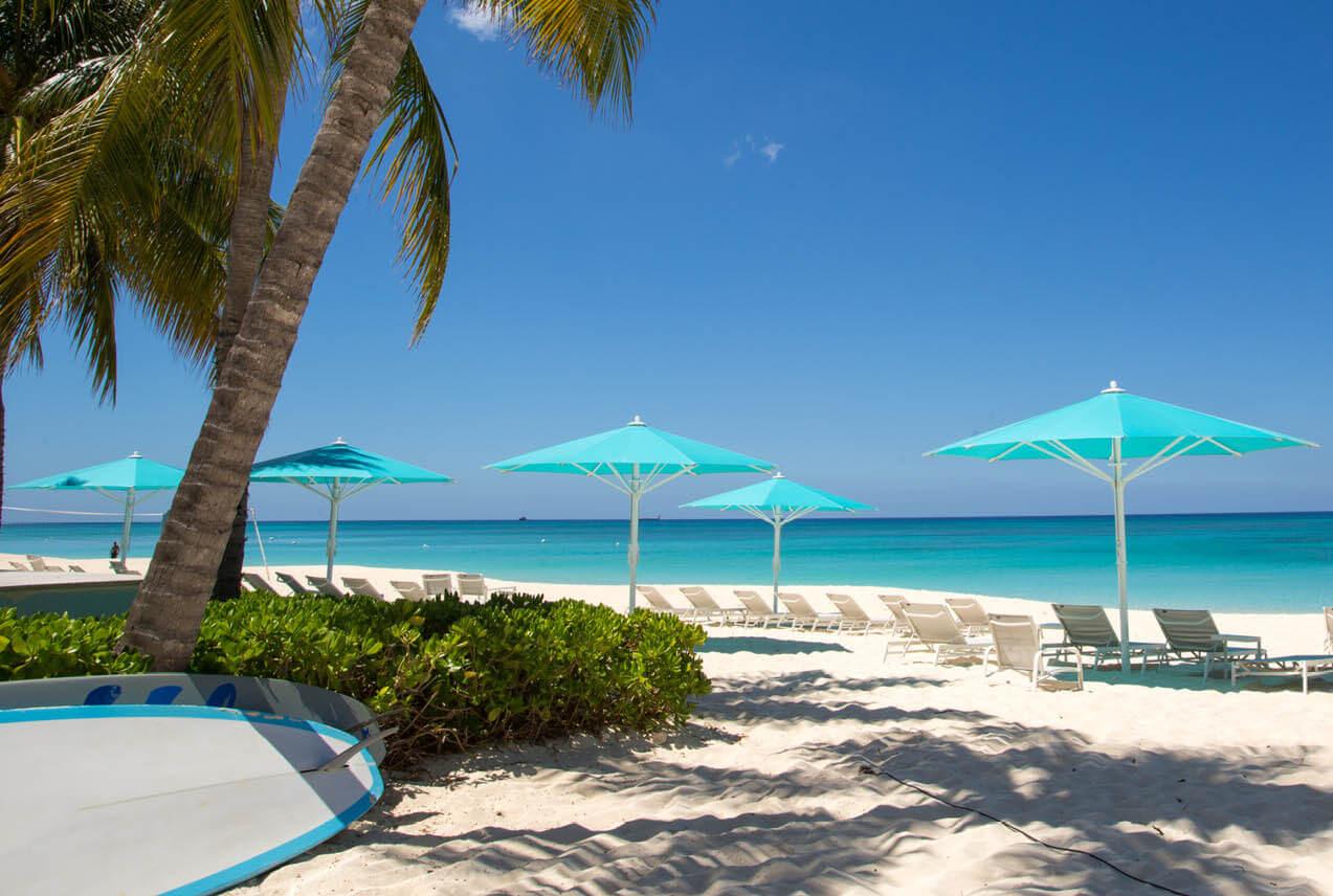 A serene beachfront with turquoise umbrellas on Seven Mile Beach in the Cayman Islands