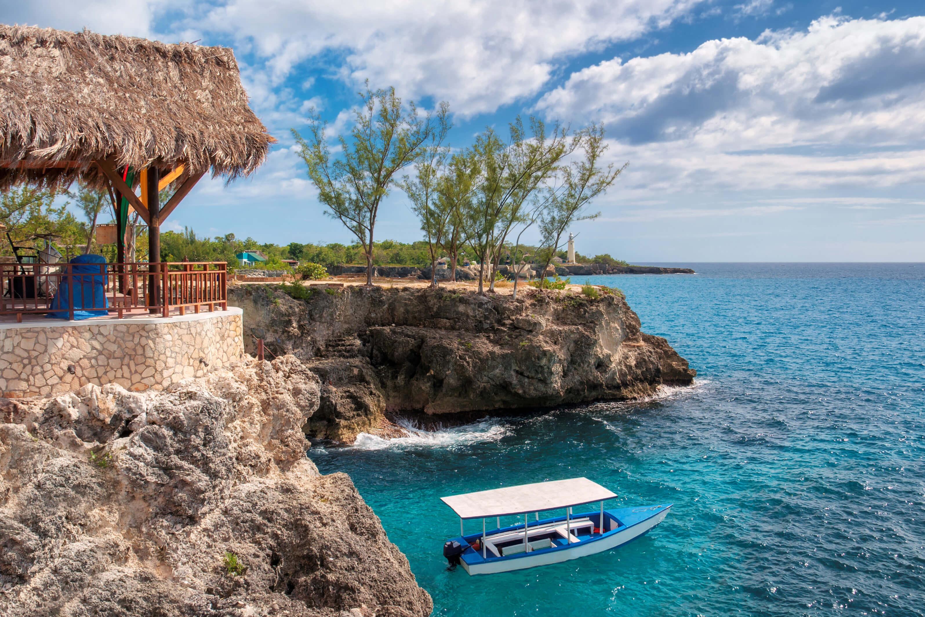 A small boat near a cliff and turquoise waters in Negril, Jamaica