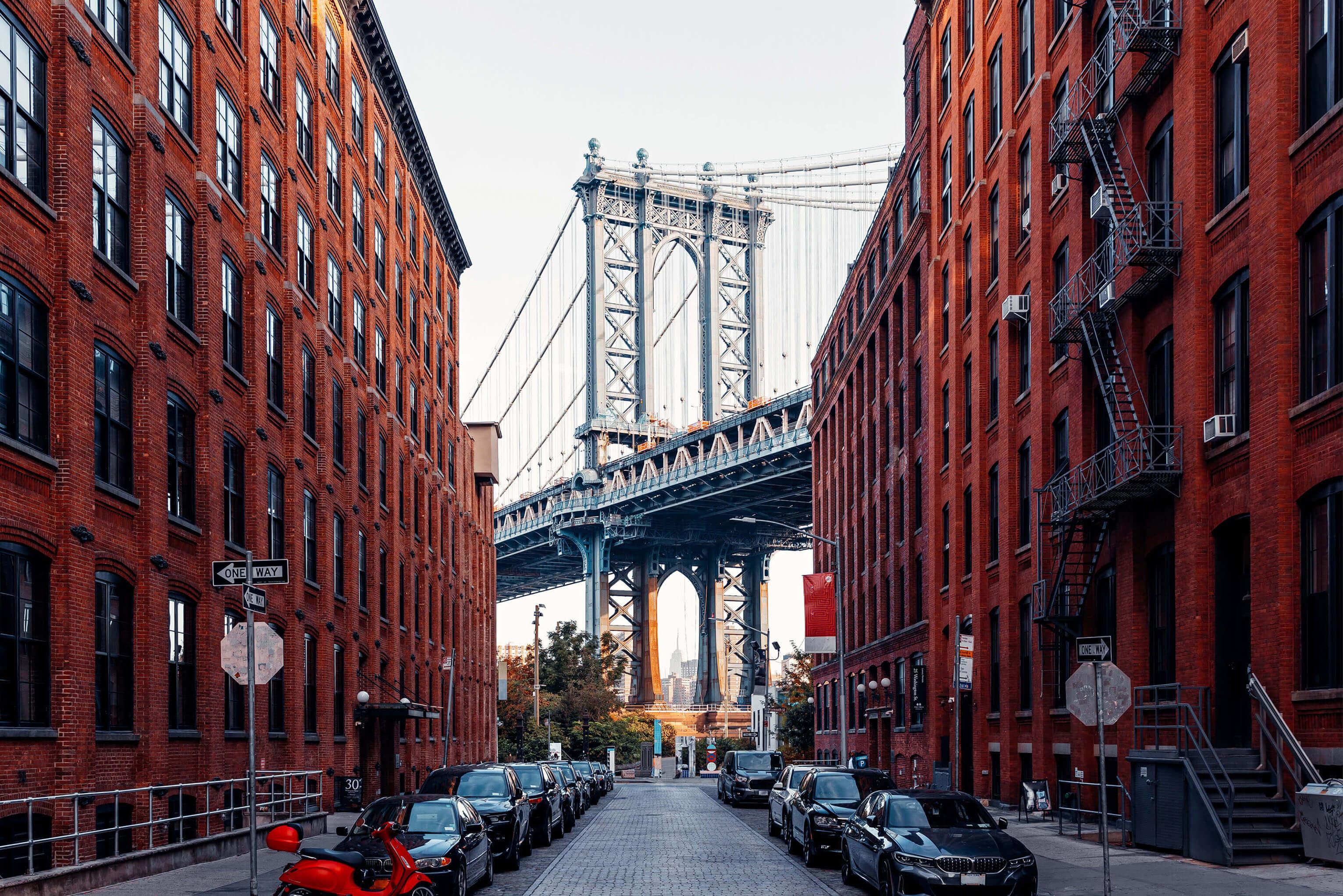 New York City street lined with buildings leading to large bridge