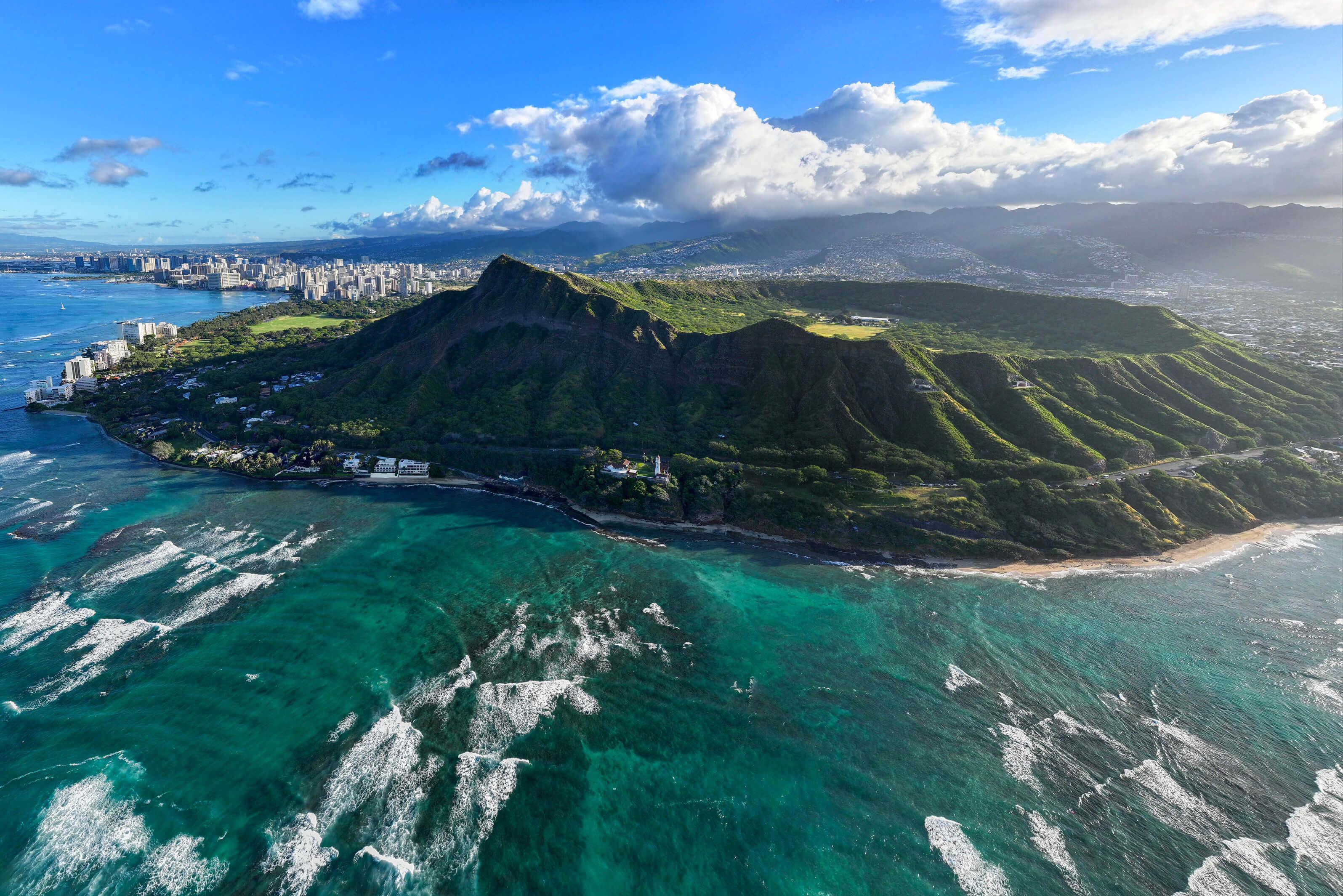 Dramatic landscape of Oahu, Hawaii, featuring ocean waves, tall cliffs, and lush greenery