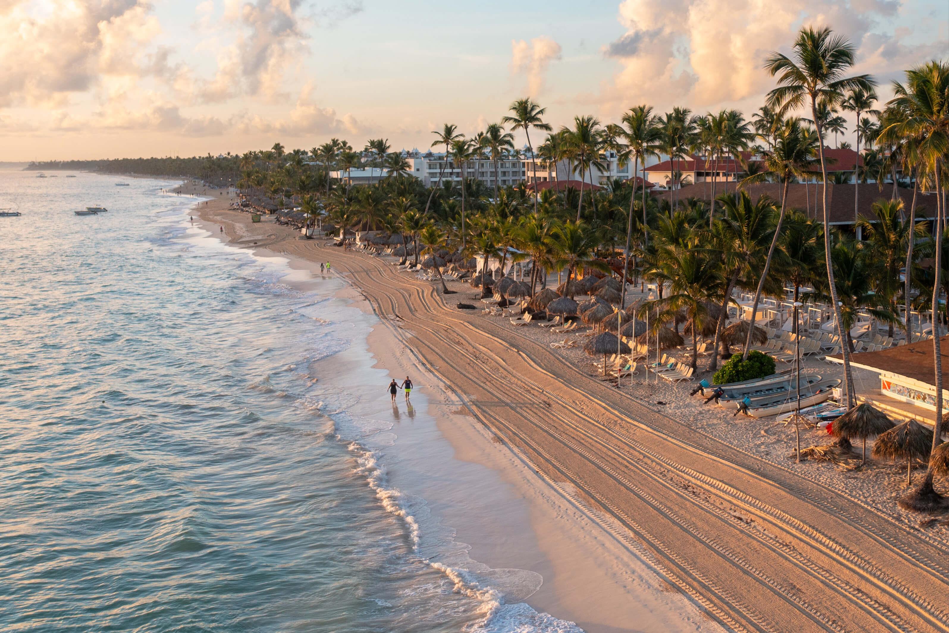 Long coast at sunset lined with tall palm trees and resorts in Punta Cana, Dominican Republic