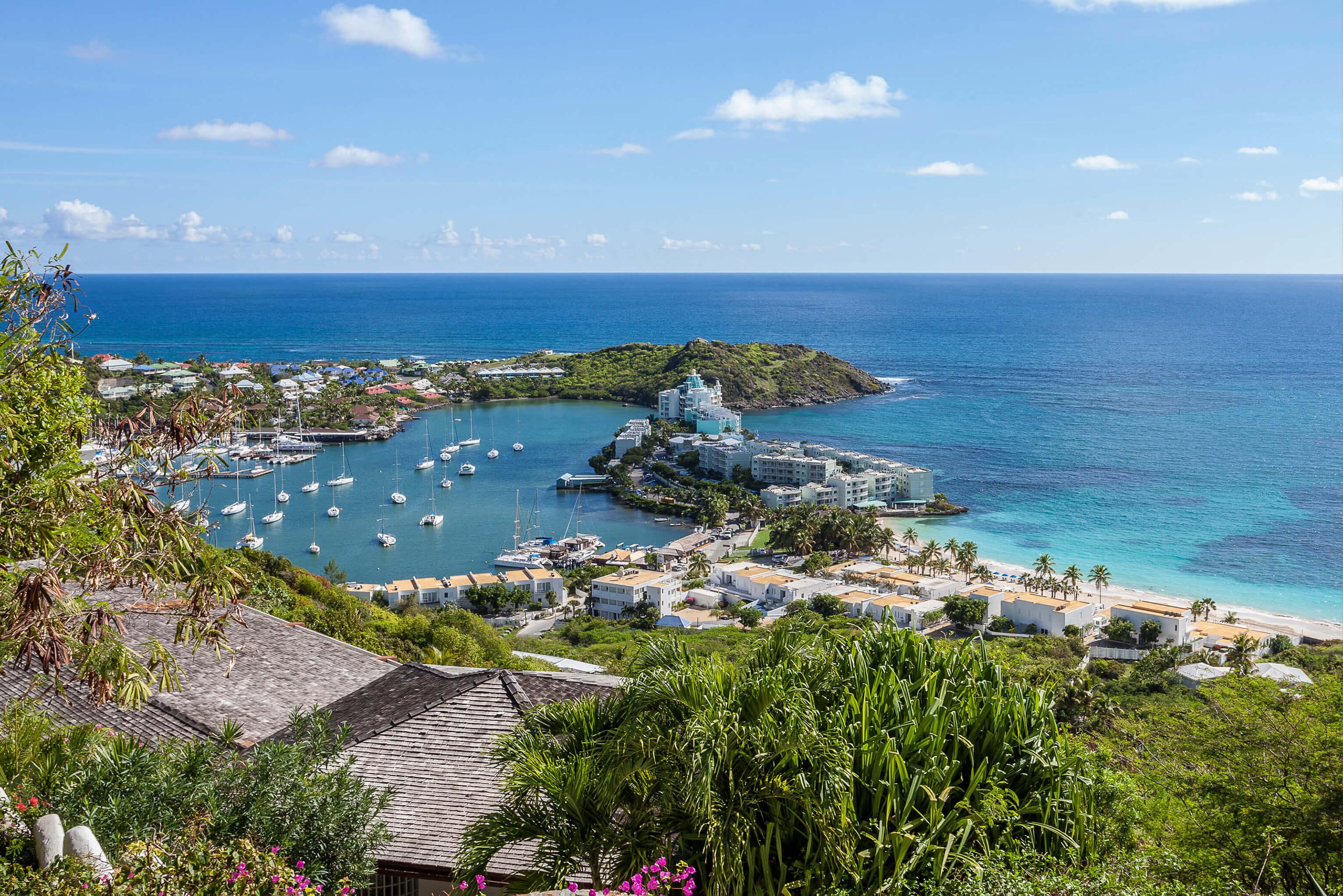View of a bay in St. Martin with boats from a hillside, showcasing water and landscape under a clear sky
