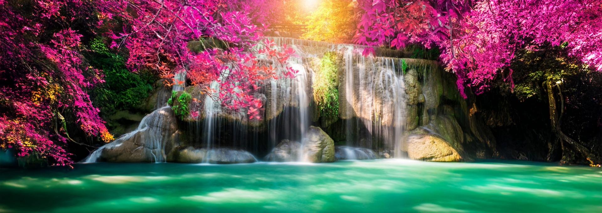 Waterfall with turquoise water and bright pink leaves in sunlight