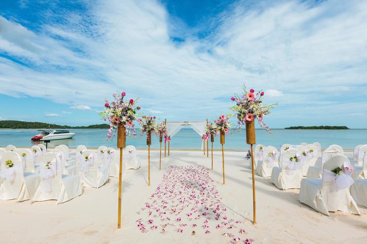 Wedding altar on sandy beach with white chairs and flowers by the ocean