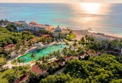 Aerial view of a beachfront resort with pools and palm trees featuring Iberostar Beachfront Resorts.