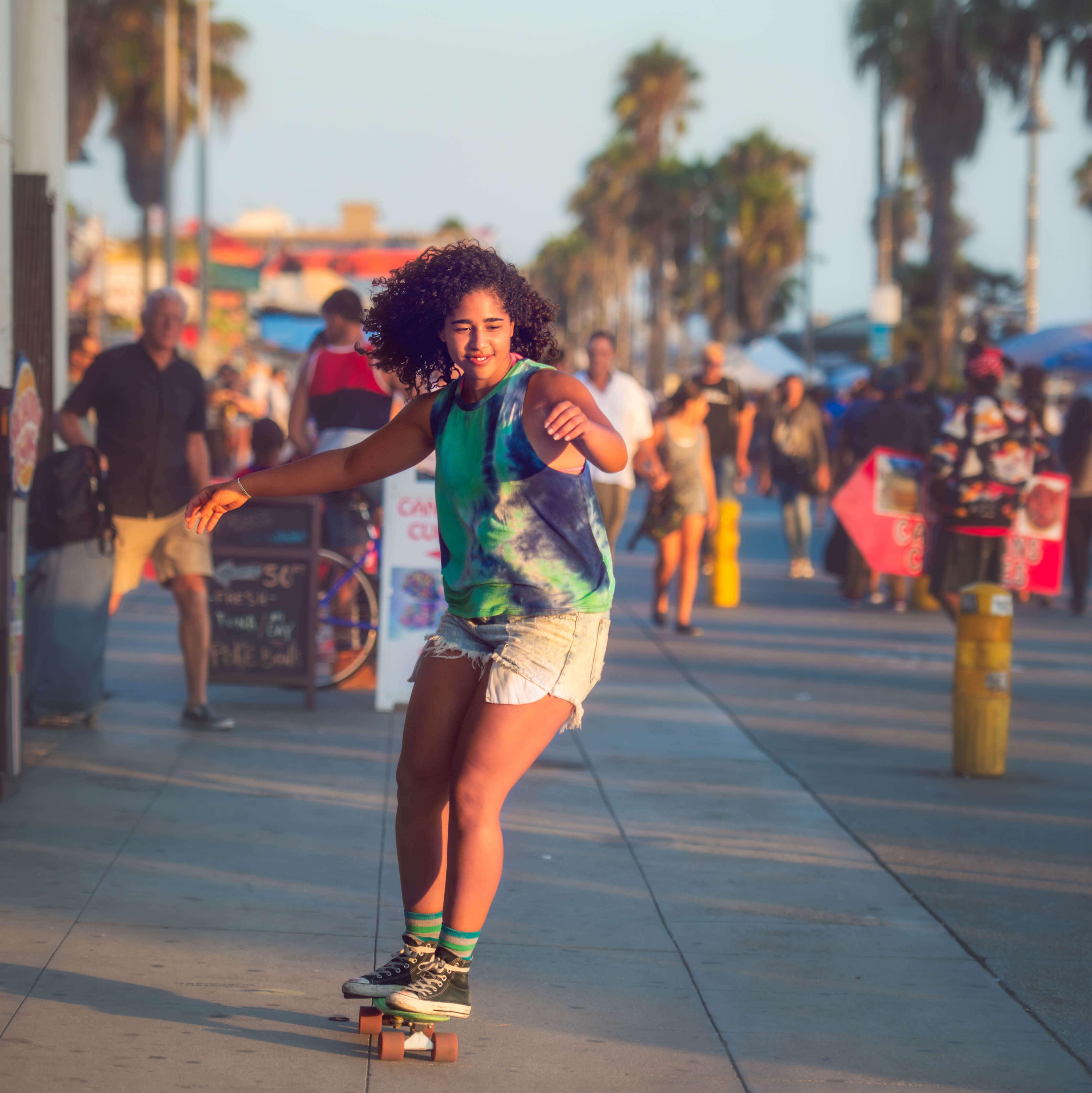 A woman skateboards along a populous area of Los Angeles