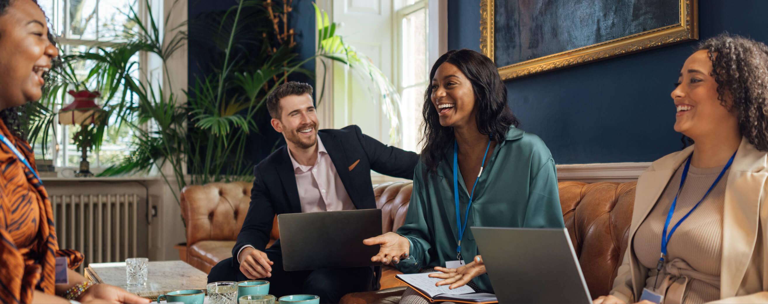 A group of coworkers smile while working from a hotel lobby