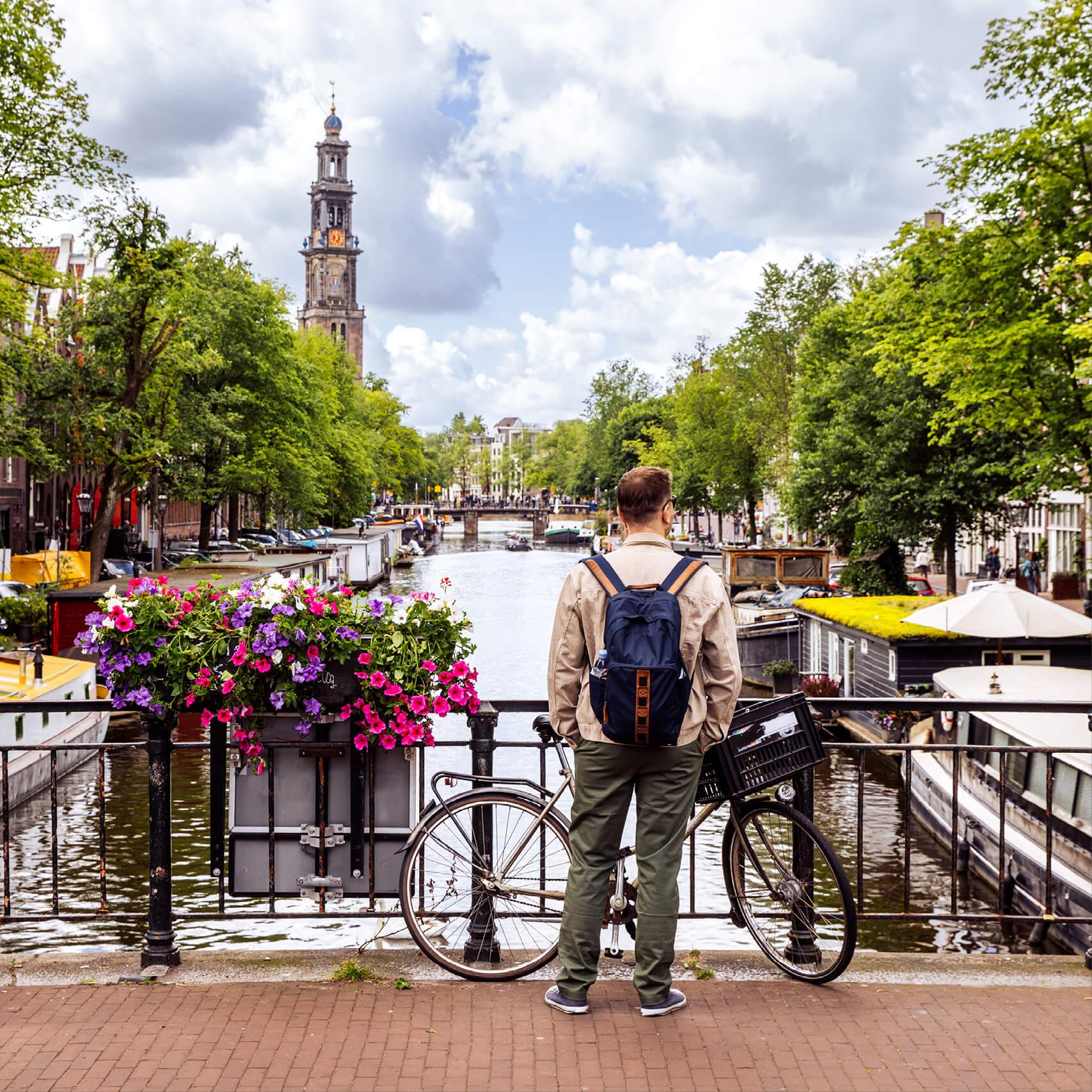 A man with a bicycle faces a waterway in Amsterdam