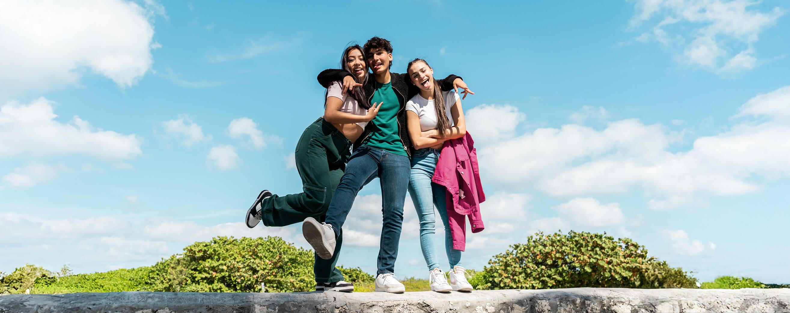 A trio of older student pose while on a group trip