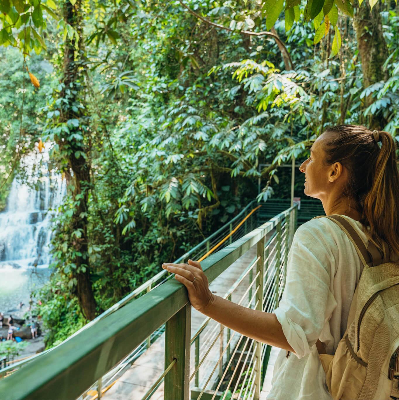 A woman looks at a waterfall in a forest setting