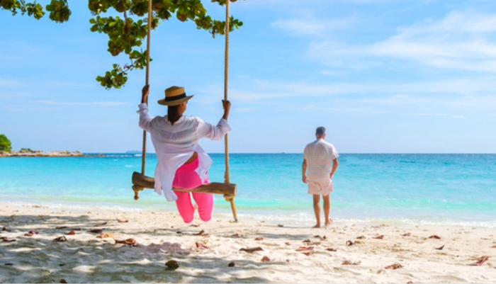 Couple enjoying a tropical beach with clear blue water and tree swing