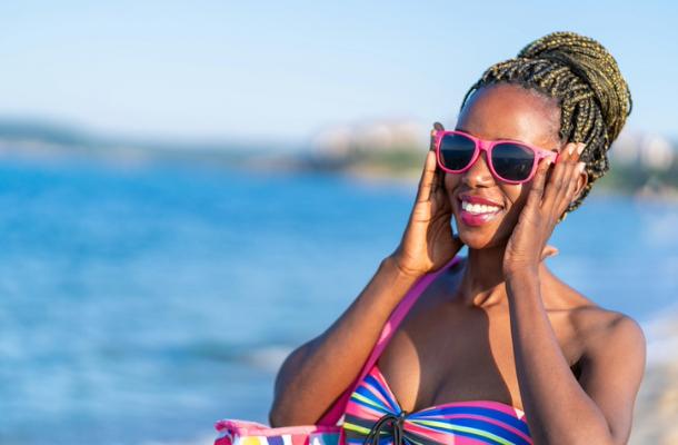 Woman smiling in bright sunglasses on a sunny beach shoreline