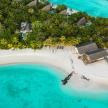 Tropical island in Indian Ocean featuring huts surrounded by lush green trees and clear blue waters